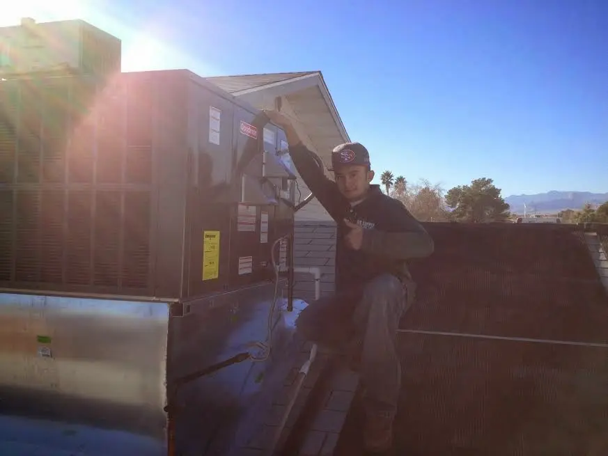 HVAC technician performing Air Duct Cleaning on a rooftop unit in Prien
